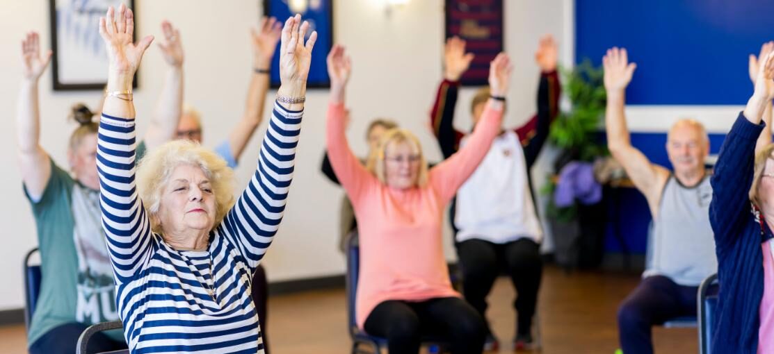 seniors exercising in chair with hands up
