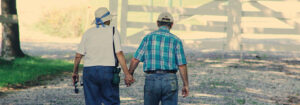 elderly couple holding hands and walking outside
