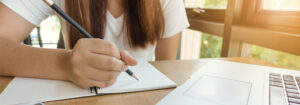 women holding pencil sitting at table