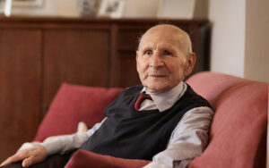 An elderly man sitting on a couch in a living room