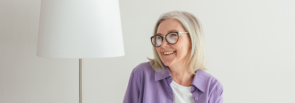 A woman with glasses and a purple shirt smiling