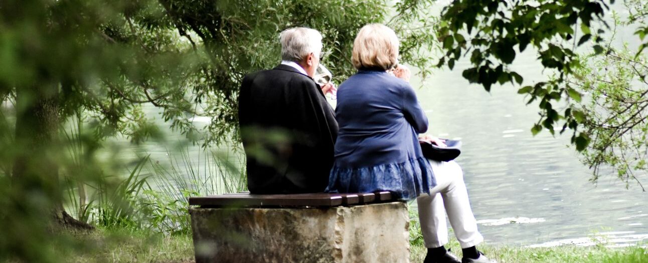 couple sitting by water under tree
