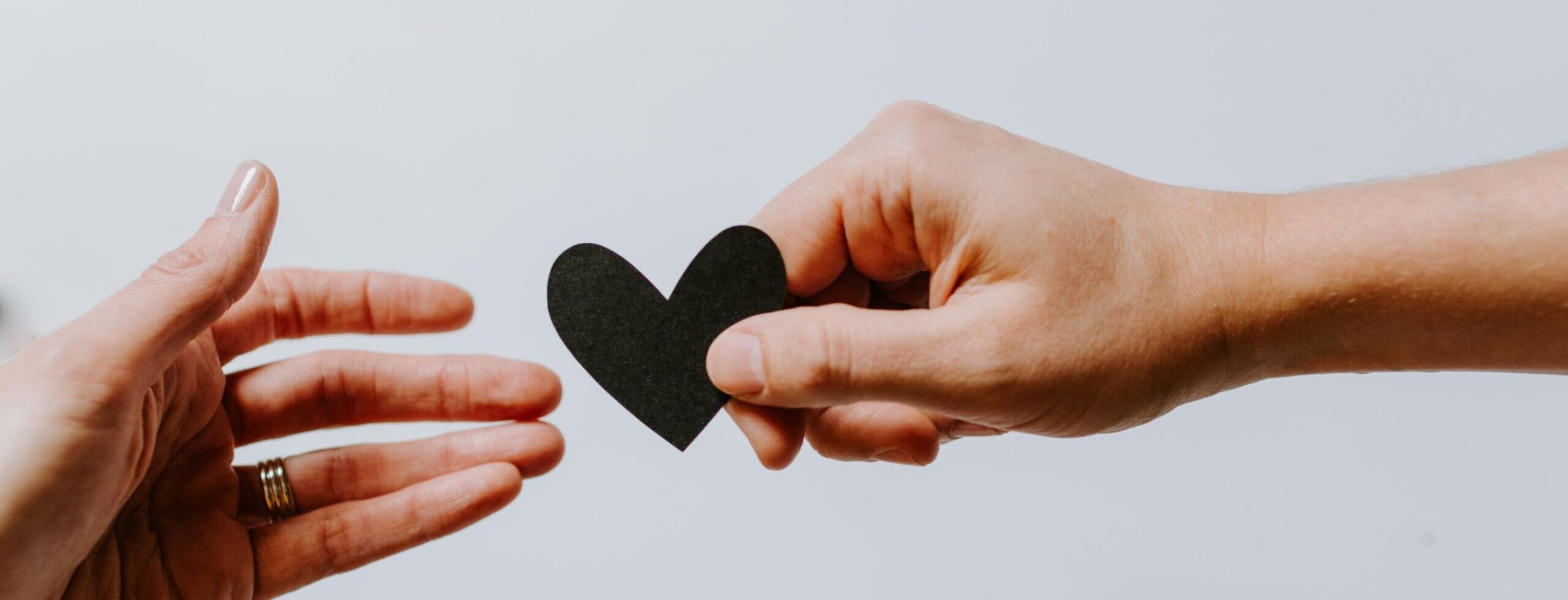 hands grabbing a black paper heart