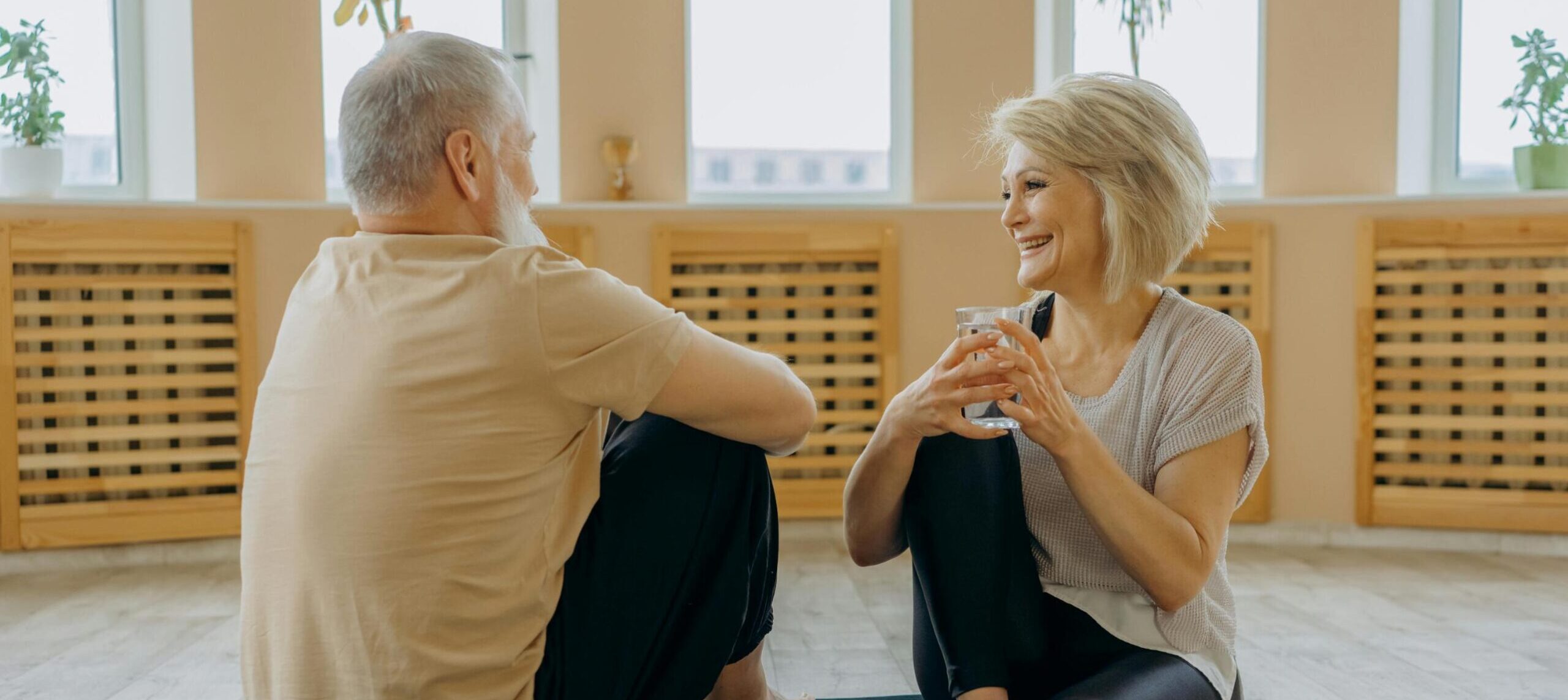 An Elderly Man and Woman Having Conversation while Sitting on Yoga Mats